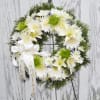 White floral wreath with a ribbon on a stand