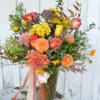 Mixed bouquet of roses, dahlias, and yellow blooms in a glass vase