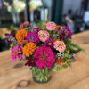 Bright mixed bouquet of pink, orange, and purple flowers in a glass vase