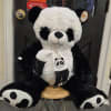 Large black-and-white panda plush toy sitting on a stool