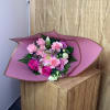 Pink bouquet with roses, carnations, and a daisy-like bloom wrapped in mauve paper