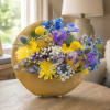 Mixed bouquet in a gold crescent vase with yellow, blue, and purple flowers