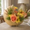 Peach roses and yellow daisies arranged in a gold crescent vase