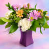 Mixed bouquet of pink, peach, and white flowers in a purple vase