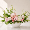 Pink and white floral arrangement in a white bowl vase