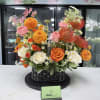 Basket arrangement of orange, pink, and white flowers