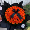 Bouquet of orange roses wrapped in black paper with a black ribbon