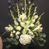 White floral arrangement in a glass vase with tall blooms and greenery