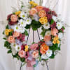 Heart-shaped floral wreath with roses and daisies on a stand