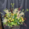 Large mixed floral arrangement with orange blooms and tall grasses