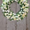 White floral wreath with lilies and roses on a wooden background
