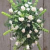 White roses and daisies arranged with green spikes in a starburst design