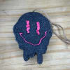 Black skull-shaped hanging ornament with a pink smiley face