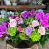 Pink roses and purple orchids in a low floral arrangement