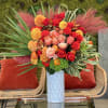 Bright bouquet of red, pink, and orange flowers in a white vase