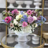 Mixed pastel flower arrangement in a white pedestal vase