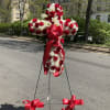 Standing floral cross of red roses and white flowers with red ribbon