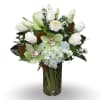 White roses and green orchids arranged with blue hydrangea in a glass vase
