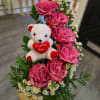 Pink roses with a teddy bear in a wooden container
