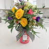Bouquet of yellow, pink, purple, and white flowers in a pink candle jar