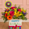 Birthday flower arrangement in a striped gift box with a colorful topper