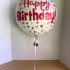 Round foil balloon reading Happy Birthday with heart and star confetti