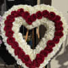 Heart-shaped floral wreath of red roses and white flowers on an easel