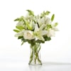 White lilies and roses arranged in a clear glass vase