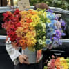 Large rainbow bouquet in a silver bucket held by a person