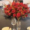 Large red rose centerpiece with orange accents on a banquet table