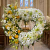 Heart-shaped floral wreath on an easel with white and yellow flowers