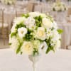 White floral arrangement in a pedestal vase with green accents