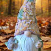 Decorative gnome figurine holding pinecones on an autumn background