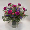 Bouquet of magenta carnations and purple filler flowers in a glass vase