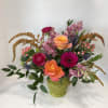 Mixed bouquet of roses, gerbera daisies, and pink blooms in a green vase