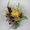 Mixed bouquet of yellow and purple flowers in a glass vase with ribbon