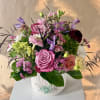 Pink and purple mixed flower arrangement in a white vase