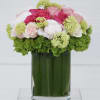 Pink and white roses arranged in a green glass vase