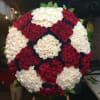 Large circular arrangement of red, white, and dark blue roses on an easel