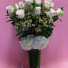 White roses and hydrangeas in a tall glass vase