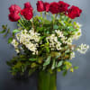 Red roses arranged in a green glass vase with white filler flowers