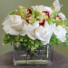 White roses and green orchids in a clear square vase