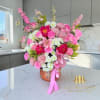 Pink and white mixed flower arrangement in a decorative vase with a ribbon