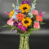 Colorful mixed bouquet in a clear glass vase with sunflowers, roses, and carnations