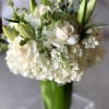 White roses and lilies arranged in a tall glass vase