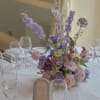 An airy, garden-inspired centerpiece with soft roses, playful pastel blooms, and delicate