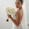 Bride holding a white rose bouquet with a veil and lace gown