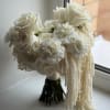 White bridal bouquet with roses and ruffled blooms, finished with trailing strands