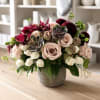 Mixed bouquet of blush roses, burgundy blooms, and succulents in a gray vase