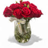 Red roses arranged in a clear glass vase with a ribbon bow